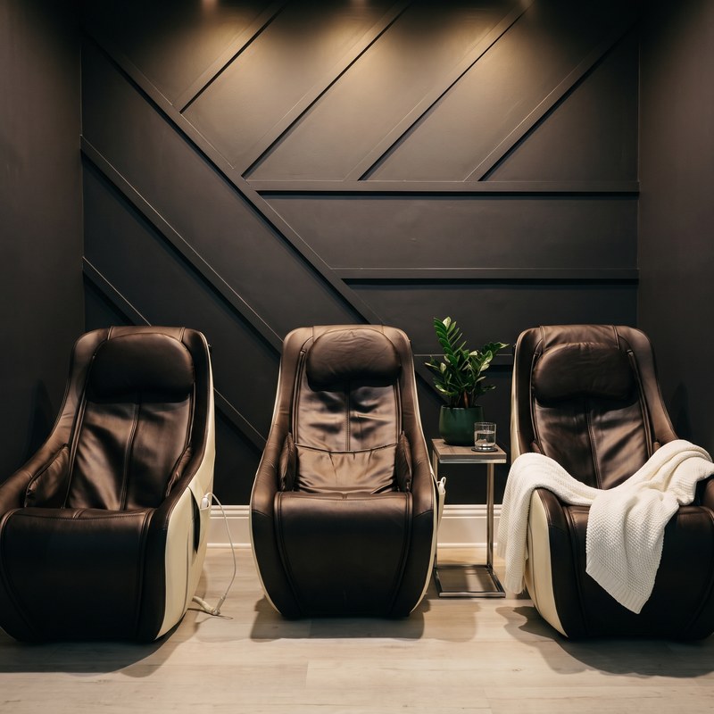 Three massage chairs in a dark-panelled lounge
